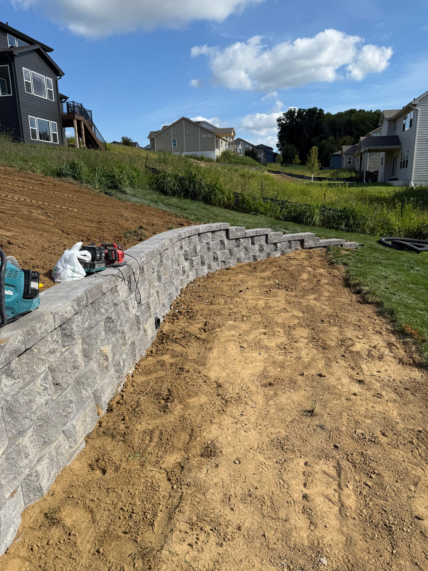 Curved block retaining wall under construction in residential neighborhood