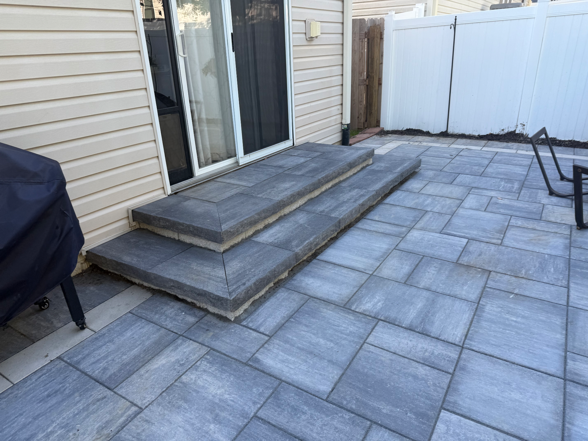 Gray paver patio with matching steps leading to home entrance
