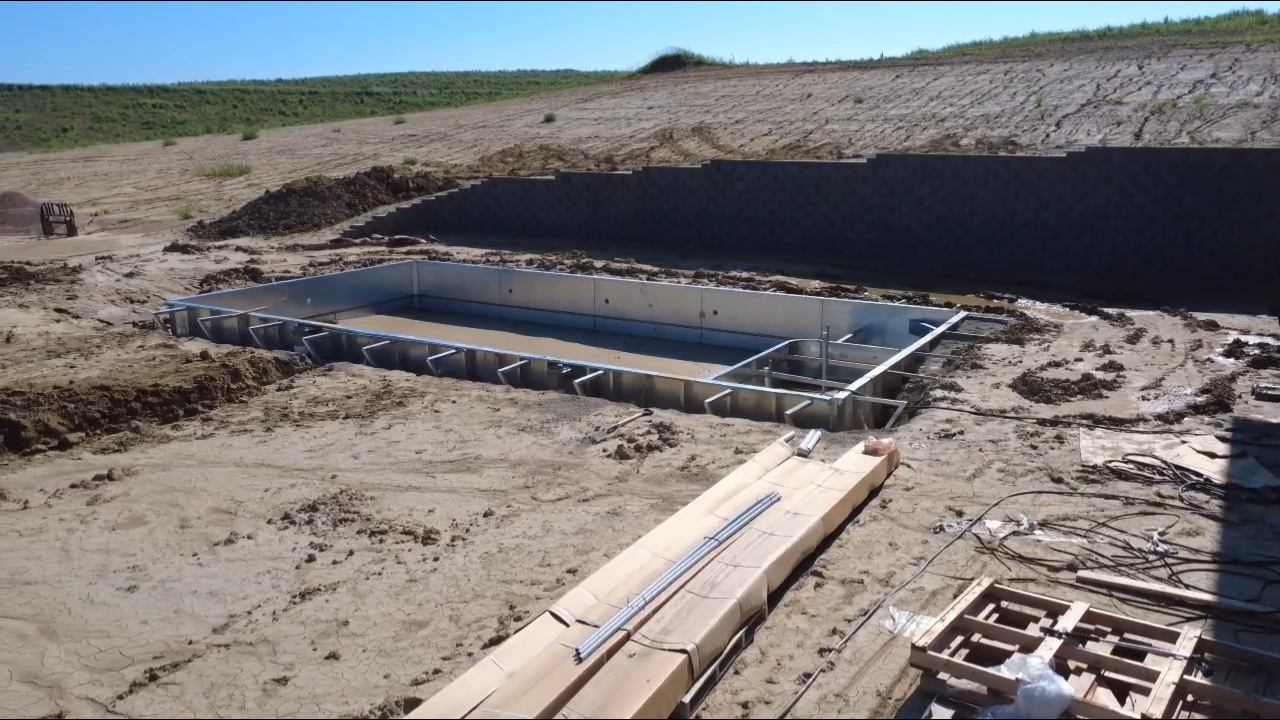 Steel wall pool frame installation with retaining wall construction