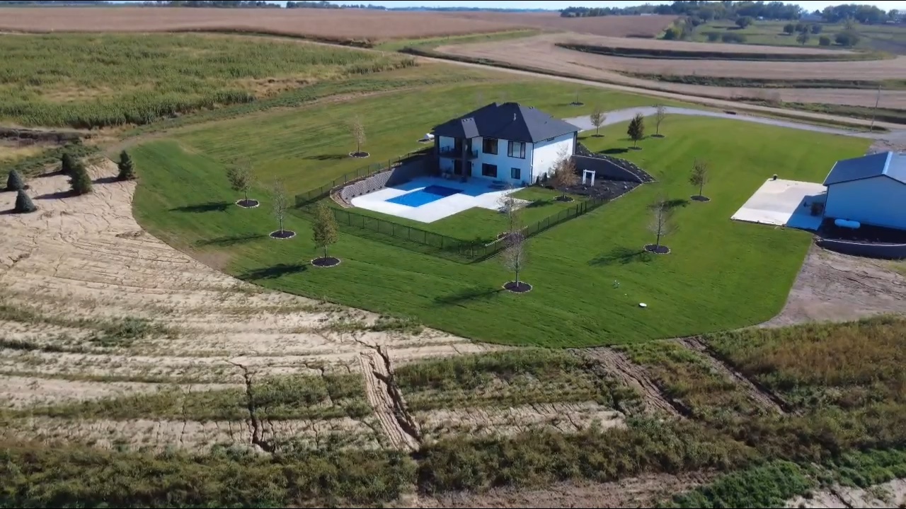 Rectangular in-ground pool with mature landscaping and red Adirondack chairs