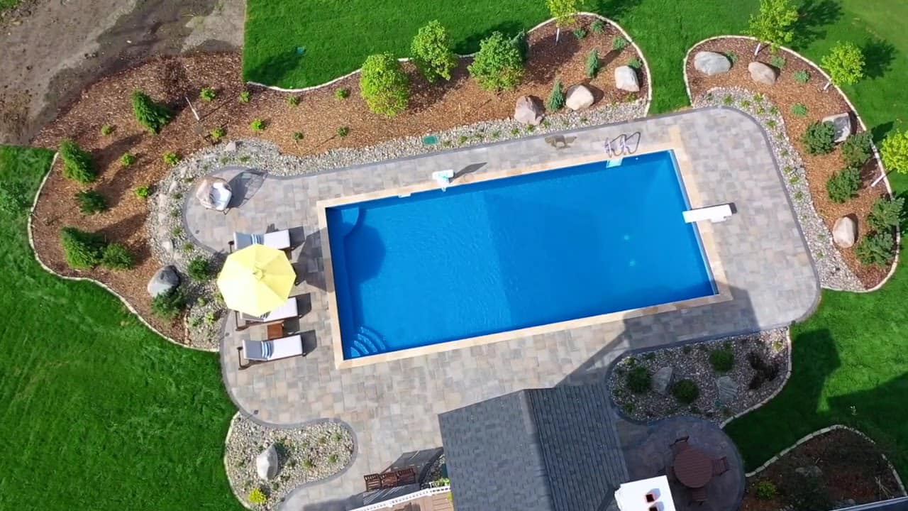 Modern rectangular pool with paver surround and umbrella seating