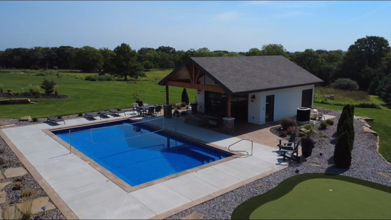 In-ground pool with water slide fountain and concrete deck fenced backyard