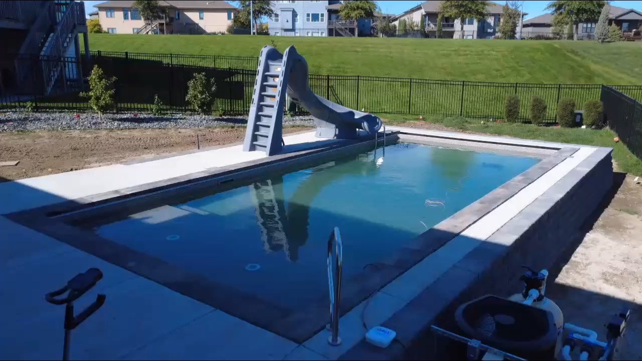 Freeform pool with stamped concrete patio and covered pergola in Omaha