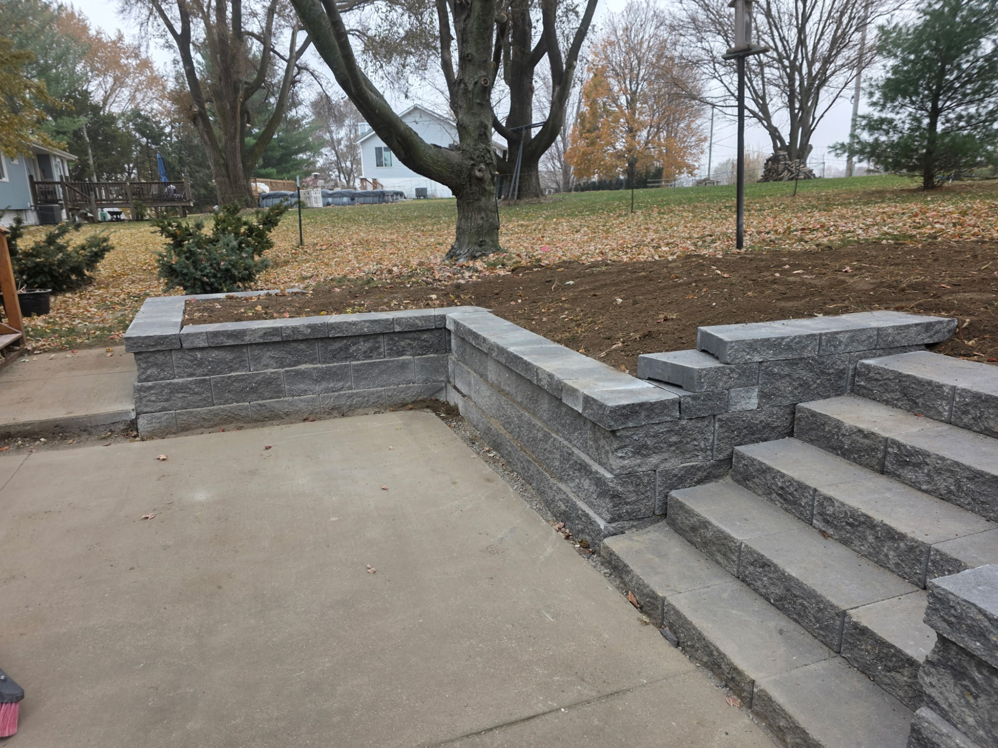 Gray block retaining wall with integrated stone steps in Omaha backyard